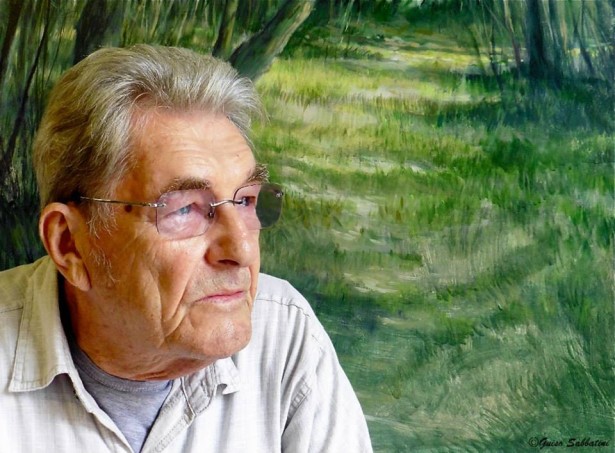 Primo piano di Brian Mobbs, artista legato alla città di Tarquinia, davanti a una sua opera