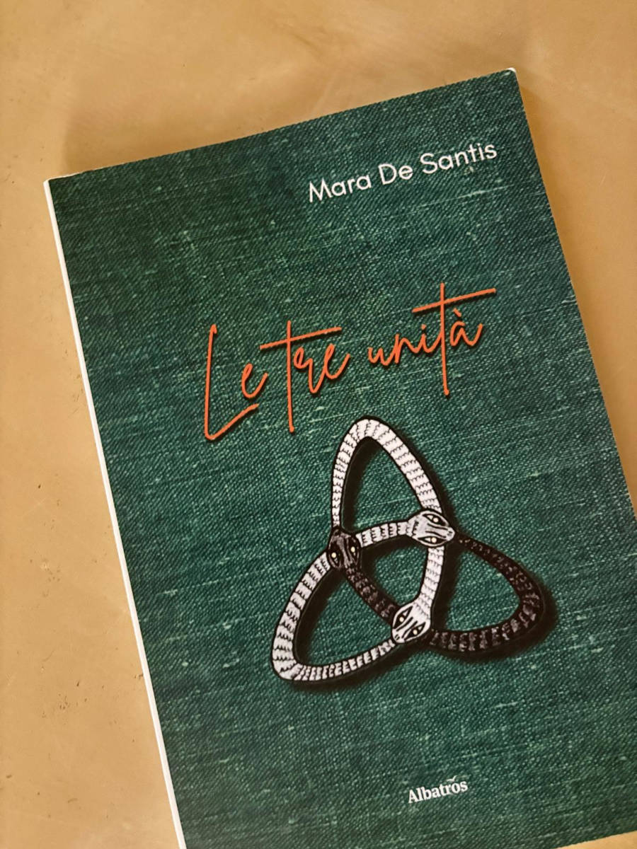 Copertina del libro "Le tre unità" di Mara De Santis, edito da Albatros, con illustrazione di tre serpenti intrecciati su sfondo verde.