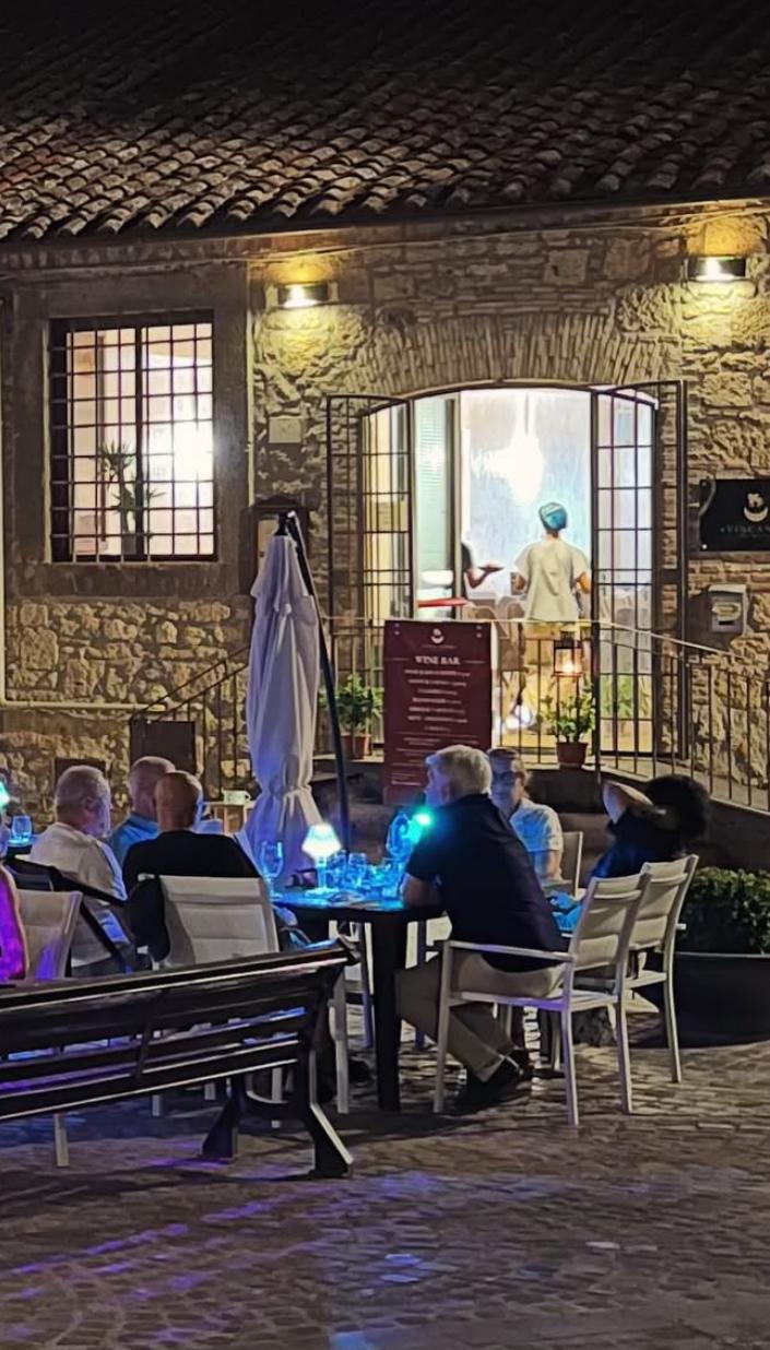 Clienti seduti ai tavoli esterni di Vincanto in Piazza San Martino a Tarquinia durante una serata estiva