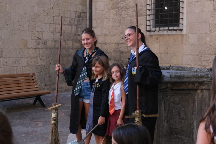 Quattro giovani partecipanti in abiti di Hogwarts con scope da Quidditch a Back to Hogwarts Tarquinia.