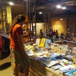 Stand di libri e pubblico durante il Festival Internazionale di Letteratura Resistente a Pitigliano 2025, con esposizioni, dibattiti e musica dal vivo.