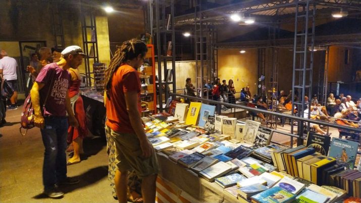 Stand di libri e pubblico durante il Festival Internazionale di Letteratura Resistente a Pitigliano 2025, con esposizioni, dibattiti e musica dal vivo.