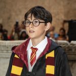 Giovane comparsa vestita da Harry Potter con mantello, occhiali e sciarpa Grifondoro durante l’evento Back to Hogwarts 2025 a Tarquinia.