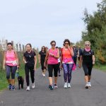 Gruppo di donne in maglia rosa che cammina durante la Camminata Rosa a Tarquinia Lido, passeggiata solidale della Nature Run 2025 tra mare e Oasi delle Saline.