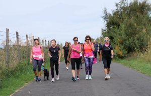Gruppo di donne in maglia rosa che cammina durante la Camminata Rosa a Tarquinia Lido, passeggiata solidale della Nature Run 2025 tra mare e Oasi delle Saline.
