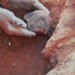 Mani con guanti sollevano un reperto etrusco durante gli scavi nella necropoli dei Monterozzi di Tarquinia